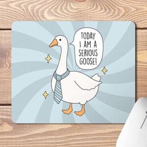 May include: A blue and white mouse mat featuring a cartoon goose wearing a blue and white tie. The goose is saying "Today I am a serious goose!" in a speech bubble.