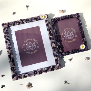 May include: Two amethyst crystal picture frames with a purple background and gold lettering that reads "The Aurora Palace 2020 handmade".
