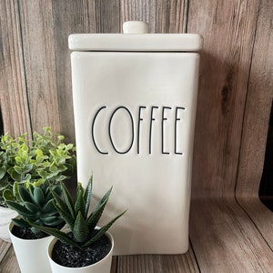May include: White ceramic coffee canister with a black lid and the word "COFFEE" written in black on the front.