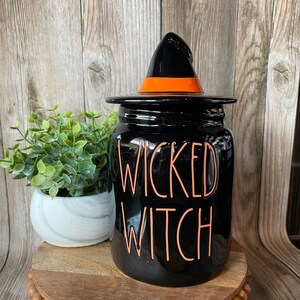 May include: Black ceramic jar with a witch hat lid. The jar has the words "Wicked Witch" written in orange on the front.