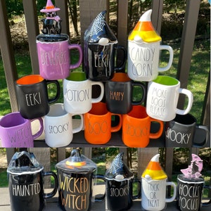 May include: A collection of 12 Halloween-themed ceramic mugs with various designs and sayings. The mugs feature spooky characters, such as witches, ghosts, and candy corn. Some of the sayings on the mugs include "Beware", "EEK!" and "Spooky".