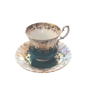 May include: A vintage teacup and saucer set. The teacup has a white interior and a teal exterior with gold floral accents. The saucer is white with a gold rim and teal center, also with gold floral details. The handle is white.