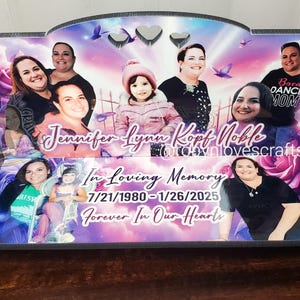 May include: A black wooden bench with a purple, pink, and white photo collage. The collage features multiple people and the text "Jennifer Lynn Kopf Noble" and "In Loving Memory 7/21/1980 - 1/26/2025 Forever In Our Hearts".