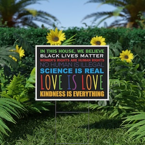 Puede incluir: Un letrero de jard&iacute;n rectangular negro con borde blanco que presenta el texto: IN THIS HOUSE, WE BELIEVE, BLACK LIVES MATTER, WOMEN'S RIGHTS ARE HUMAN RIGHTS, NO HUMAN IS ILLEGAL, SCIENCE IS REAL, LOVE IS LOVE, y KINDNESS IS EVERYTHING.