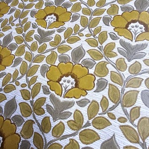 May include: Wallpaper featuring a repeating floral pattern with mustard yellow flowers and sage green leaves on a white background. The design includes embossed textures that create a raised effect for the petals and foliage across the surface.