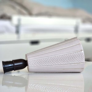 Può includere: Un paralume in ceramica bianca con un motivo a chevron e un portalampada in metallo nero.