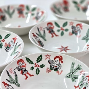 May include: Set of five white ceramic bowls with a Christmas theme. The bowls feature a red and green design with illustrations of elves and holly.