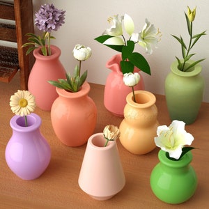 Könnte beinhalten: Eine Sammlung kleiner, farbenfroher Keramikvasen, jede mit einer einzelnen Blume oder einem kleinen Blumengesteck. Die Vasen sind in den Farbtönen Rosa, Orange, Grün, Gelb und Lila gehalten. Die Blumen umfassen Gänseblümchen, Lilien und andere Blüten.