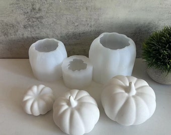 May include: A collection of white pumpkin-shaped molds and finished pumpkins. The molds are in various sizes and shapes, with a smooth, matte finish. The finished pumpkins have a textured surface and stems.