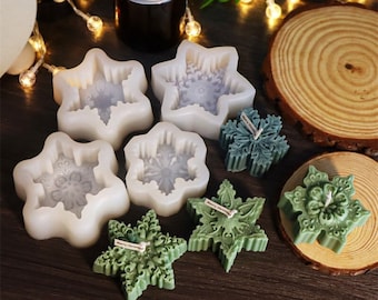 May include: A collection of snowflake-shaped candles and molds. The candles are various shades of green and blue, with intricate snowflake designs. The molds are white and star-shaped. Some candles have a "Merry Christmas" tag.