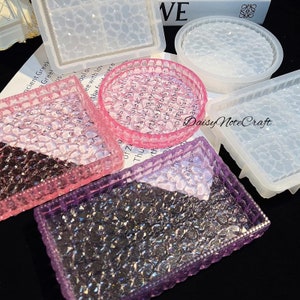 May include: A collection of resin molds in various shapes, including square, rectangular, and circular designs. The molds are in clear, pink, and purple hues, with a textured, bubble-like pattern. The image also shows the text "Daisy Note Craft".