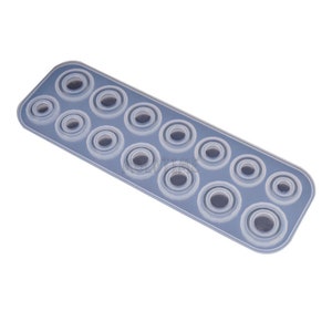 May include: A rectangular, translucent silicone mold with multiple circular cavities of varying sizes. The mold is designed for crafting small, round objects, likely for resin or other craft projects. The cavities are arranged in rows.