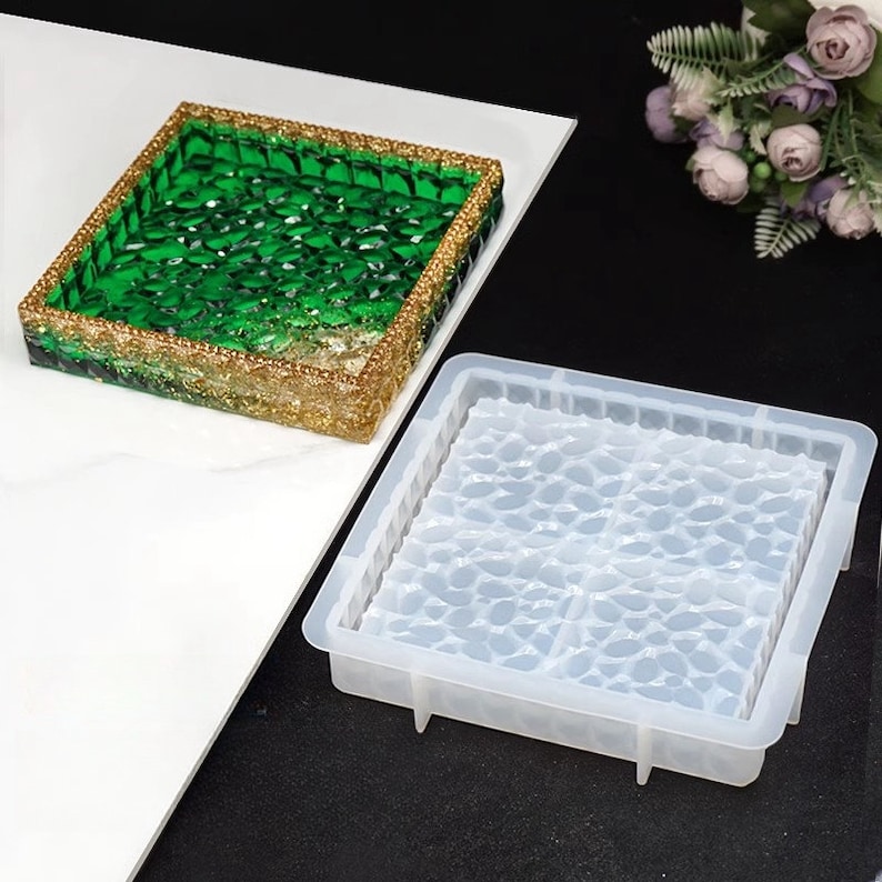 May include: Square resin tray with a green and gold design. The tray has a textured surface with a gold glitter border. A clear silicone mold with a leaf pattern is next to the tray.