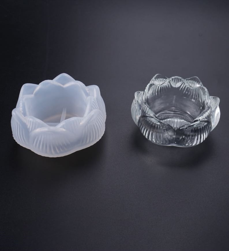 Puede incluir: Dos candelabros con forma de loto. Uno est&aacute; hecho de material transl&uacute;cido esmerilado y el otro de vidrio transparente. Ambos tienen dise&ntilde;os detallados de p&eacute;talos y est&aacute;n sobre un fondo oscuro. Estos portavelas decorativos son ideales para velas o peque&ntilde;os objetos.
