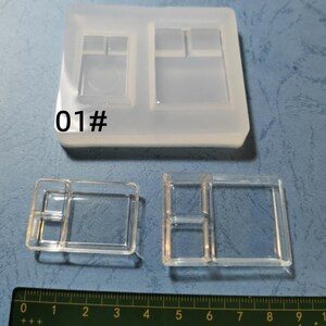 May include: A clear silicone mould with multiple rectangular and square cavities, alongside two cast resin pieces. The mould has the number "01#" printed on it. A ruler is at the bottom, showing measurements in centimetres.