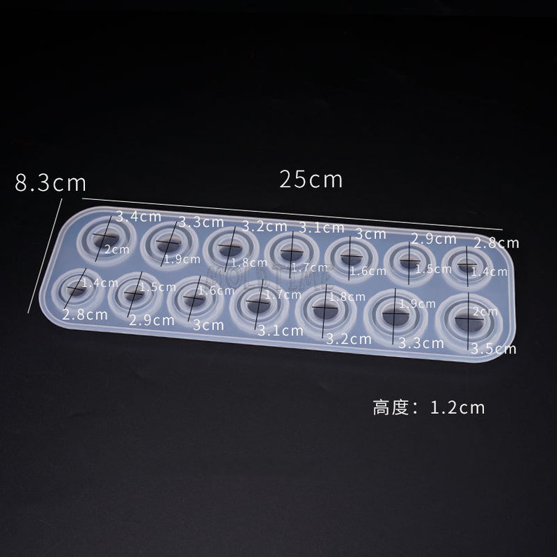 May include: A clear silicone mold with 14 circular cavities of varying sizes, designed for crafting. The mold is rectangular, measuring 25 cm long and 8.3 cm wide, with a height of 1.2 cm. Each circle's diameter is labeled in centimeters.