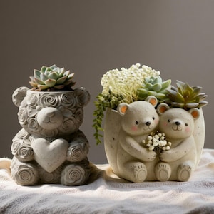 May include: Two bear-shaped planters, one with a heart and rose details, the other with two bears holding flowers. Both are filled with succulents and other greenery. The planters are a light gray color and sit on a neutral surface.