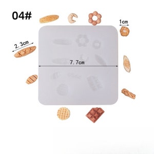 May include: A white silicone mold with various bread shapes, including a baguette, croissant, and waffle. The mold is 7.7 cm long and includes a 2.3 cm long bread shape. The image also shows several baked bread items, including a donut shape, and a 1 cm bread shape.