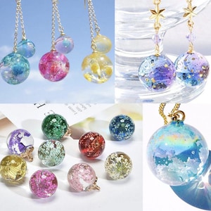 May include: Handmade resin jewellery featuring clear spheres with colourful floral and glitter inclusions. The jewellery includes earrings and pendants with gold-coloured chains. The spheres are filled with dried flowers and other decorative elements.