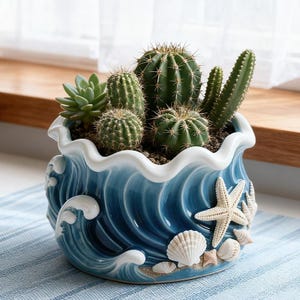 May include: A ceramic planter with a blue wave design, adorned with seashells and a starfish. The planter holds a variety of green cacti and succulents, creating a coastal theme. The rim of the planter is white.