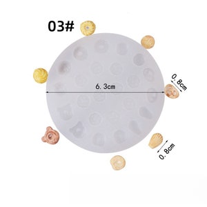 May include: A clear silicone mold with various shapes, including circles, bears, and shells. The mold is 6.3 cm in diameter and has several small, finished resin pieces around it. The text "03#" is in the upper left corner.