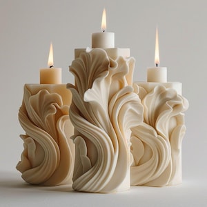 Peut inclure: Trois bougeoirs ivoire avec un motif de feuilles sculptées et fluides. Chaque bougeoir a une base carrée et une bougie blanche allumée sur le dessus. Les flammes sont vives sur le fond neutre, créant une ambiance chaleureuse.
