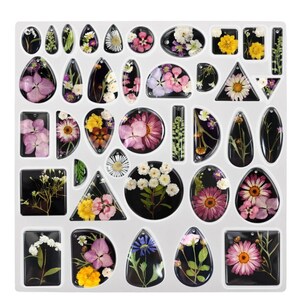 May include: A clear resin mould filled with various shapes of dried flowers. The shapes include teardrops, ovals, squares, and triangles, each with a black background. The flowers are in shades of pink, yellow, white, and purple.