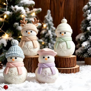 May include: Four snowman-shaped candles with white bodies and textured snowflake patterns. Each wears a different coloured hat and scarf: one with brown reindeer antlers, one with a white pom-pom hat, one with a blue hat, and one with a pink beret.