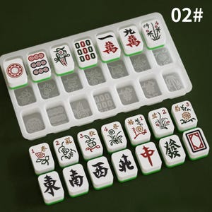 May include: A set of white and green Mahjong tiles with red and black symbols and characters. The tiles are arranged in a clear plastic tray. The image also includes the text "02#".