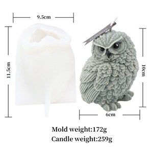 May include: A gray owl-shaped candle next to a white silicone mold. The candle is 10 cm tall and 6 cm wide. The mold is 11.5 cm tall and 9.5 cm wide. The candle weighs 259g. The mold weighs 172g. The candle has a tag that says "HANDMADE".