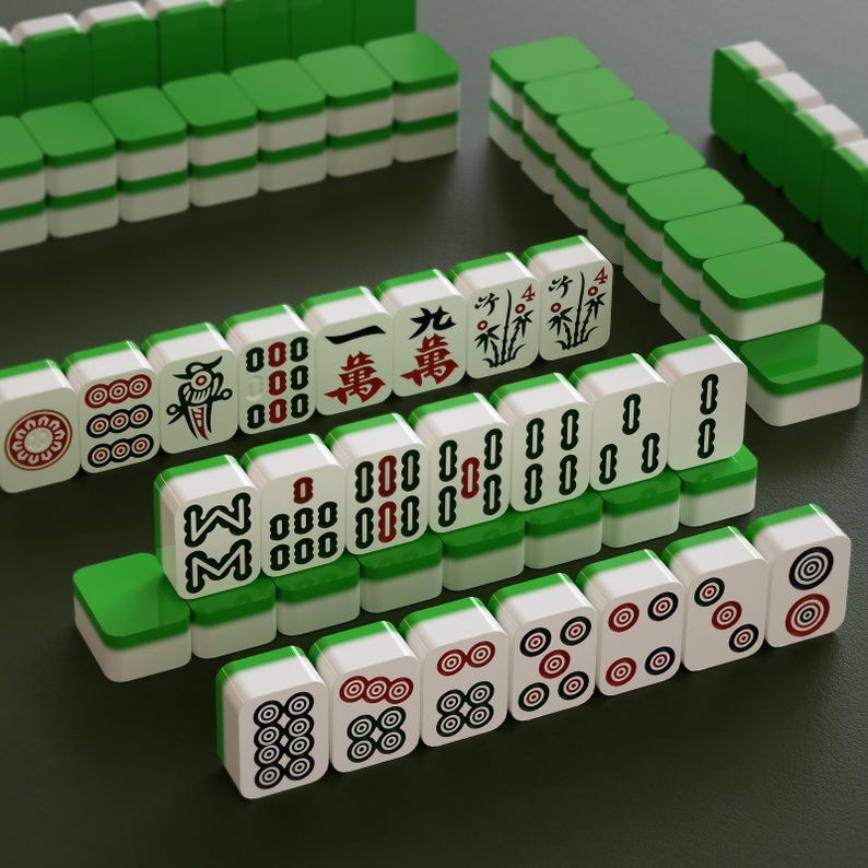 May include: A collection of white and green Mahjong tiles, featuring various symbols and characters in red and black. The tiles are arranged on a dark green surface, showcasing the game's components.