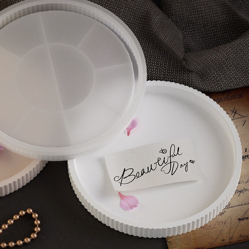 Pu&ograve; includere: Vassoio rotondo bianco con bordo scanalato e coperchio. Una piccola carta con le parole "Beautiful Day" &egrave; sul vassoio, insieme a petali di fiori rosa. Il vassoio &egrave; realizzato in materiale traslucido.