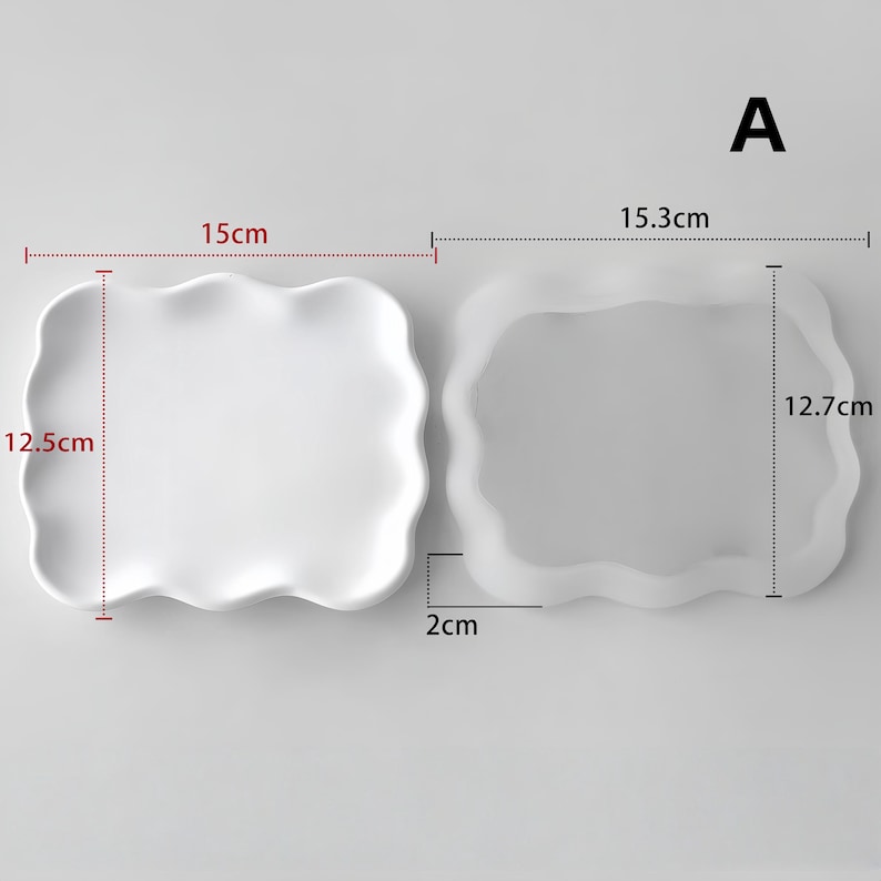 May include: Two white, wavy-edged ceramic plates. One measures 15 cm x 12.5 cm, the other 15.3 cm x 12.7 cm, with a 2 cm depth. The plates have a smooth, minimalist design, suitable for serving food or as decorative pieces.
