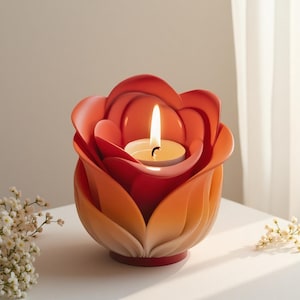 May include: A vibrant, rose-shaped candle holder in shades of red and orange, with a lit tea light candle inside. The petals have a gradient effect, and the base is a solid red. A decorative item for home decor.