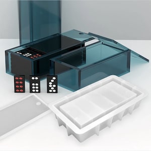 May include: A teal acrylic domino set with a matching storage box. The set includes black and white dominoes, a white tray, and a tall, rectangular container. The dominoes are displayed with their pips visible. The box is transparent.