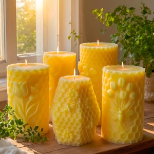 May include: Five yellow pillar candles with intricate designs. One candle has a honeycomb pattern, another features a bee and floral design, and others have tulip and floral patterns. The candles are lit, casting a warm glow.