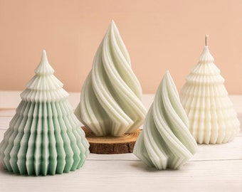 May include: Four Christmas tree-shaped candles in varying shades of green and white. The candles have unique designs, including spiral and layered textures. One candle is on a small wooden base. The background is a soft peach color.