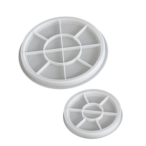 May include: Two white, circular silicone molds. The larger mold has a diameter of approximately 4 inches, and the smaller one is about 2 inches. Each mold is divided into sections by intersecting lines, creating a segmented design.
