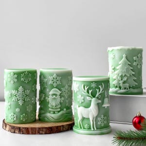 May include: Four green Christmas-themed candles with white embossed designs. One candle features snowflakes, another Santa Claus, a third a reindeer with a bell, and the last a Christmas tree and deer. The candles are on a wooden base.
