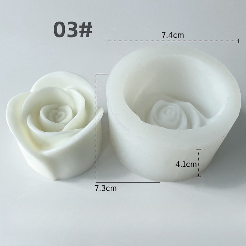 May include: A white rose-shaped candle and a white silicone mould. The mould is 7.4 cm wide and 4.1 cm tall. The candle is 7.3 cm wide. The text "03#" is in the upper left corner.