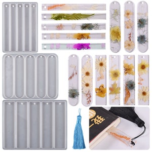 May include: The image showcases clear resin bookmark molds and finished bookmarks with dried flowers. The molds are rectangular with rounded ends and holes for tassels. The bookmarks feature various floral arrangements, and a blue tassel is also visible.