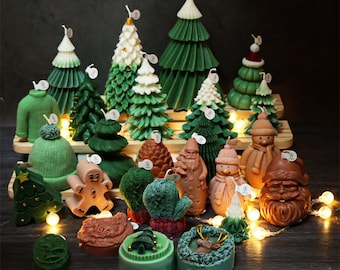 May include: A selection of Christmas-themed candles in diverse shapes, such as Christmas trees, a sweater, a gingerbread man, and Santa Claus. The candles are in shades of green, brown, and white, with detailed designs. Some candles have small tags attached.