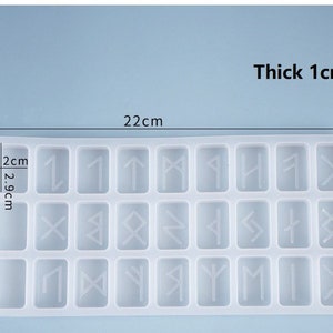 May include: A clear, rectangular silicone mold with 24 individual rune-shaped cavities. The mold is 22 cm long, 10.7 cm wide, and 1 cm thick. The dimensions of each cavity are 2.9 cm by 2 cm. The text "Thick 1cm" and measurements are visible.