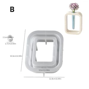 May include: A white, square-shaped flower vase with a test tube inside, and a gray flower. Next to it is a white, square-shaped mold. The mold is 12.8cm (5.04in) wide, 16.6cm (6.54in) tall, and 3.9cm (1.54in) wide. The text "B" is in the upper left corner.