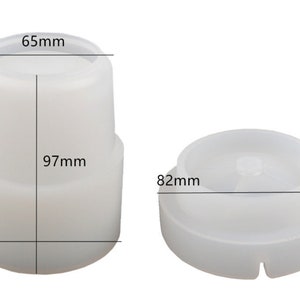 Puede incluir: Dos componentes de pl&aacute;stico blanco. Uno es cil&iacute;ndrico, de 97 mm de alto, 80 mm de ancho y 65 mm de di&aacute;metro en la parte superior. El otro es un disco, de 36 mm de alto y 82 mm de di&aacute;metro. Ambos son probablemente partes de un producto m&aacute;s grande.