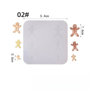 May include: A white silicone mold with six gingerbread man shapes, and three finished gingerbread men. The mold is 5.4 cm wide. The finished gingerbread men are 1.6 cm and 0.6 cm tall. The image has the text "02#".