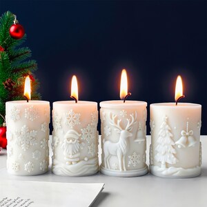 May include: Four white Christmas candles with detailed embossed designs of snowflakes, Santa Claus, a reindeer, and a Christmas tree. Each candle is lit with a warm, flickering flame, creating a festive atmosphere. The candles are arranged in a row.