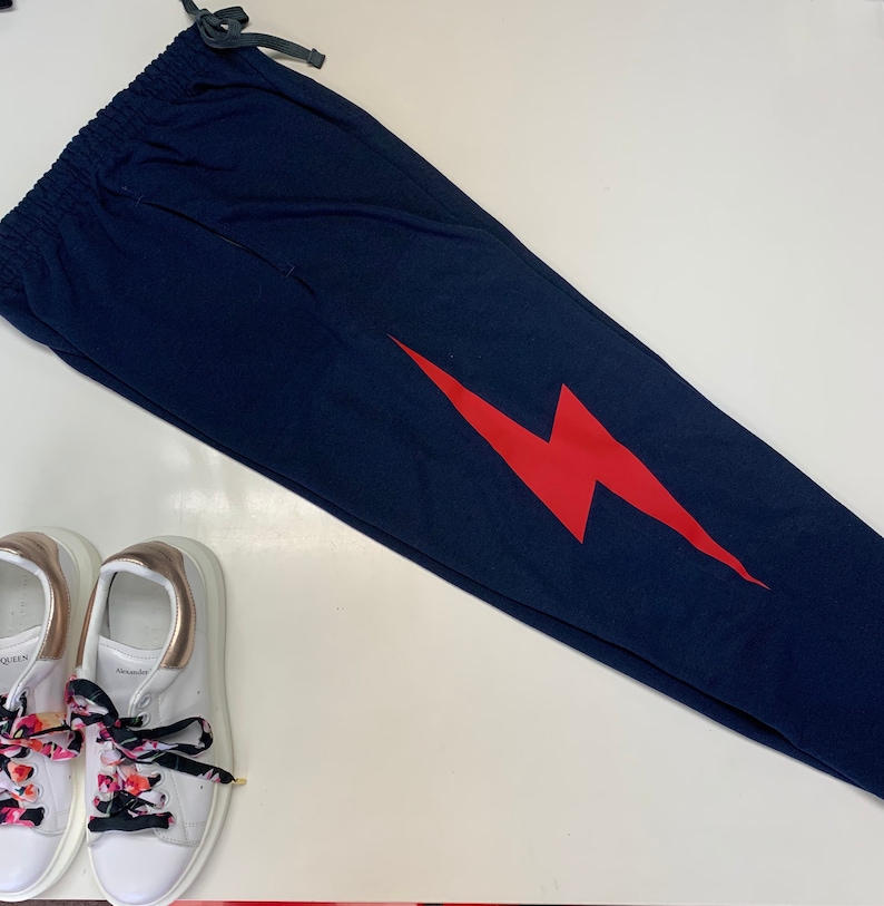 Puede incluir: Pantalones de ch&aacute;ndal azul marino con un gr&aacute;fico de rayo rojo. Los pantalones de ch&aacute;ndal tienen una cintura con cord&oacute;n.
