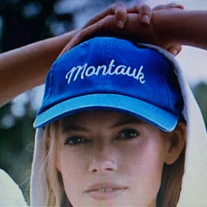 May include: A blue baseball cap with white stitching and the word "Montauk" embroidered on the front.