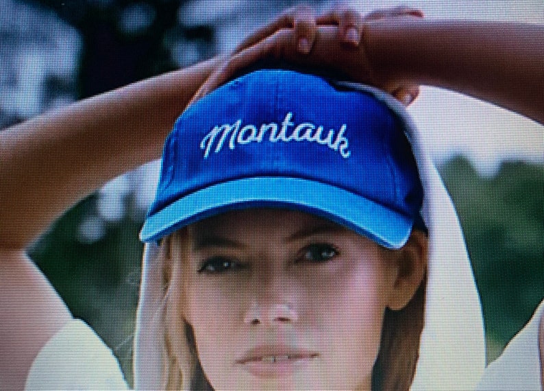 May include: A blue baseball cap with white stitching and the word "Montauk" embroidered on the front.